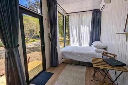 um quarto com uma cama e uma porta de vidro deslizante em Tiny House 10 at Grampians Edge em Dadswells Bridge