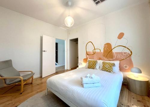 a bedroom with a bed and a chair in it at Belle Escapes - Beauty at the Beach in Glenelg
