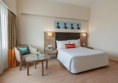 a hotel room with a white bed and a table at Greenpark Visakhapatnam in Visakhapatnam