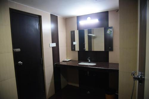 a bathroom with a sink and a mirror at Hotel Bishnu Palace in Jhārsuguda