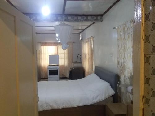 a bedroom with a white bed and a kitchen at Limbas Luxury Appartements 2 in Bakau