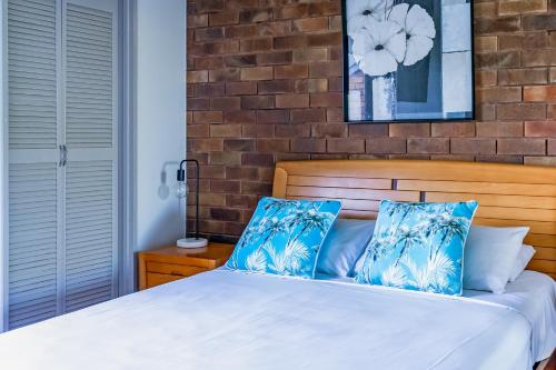 a bedroom with a bed with blue and white pillows at Glen Eden Beach Resort in Peregian Beach