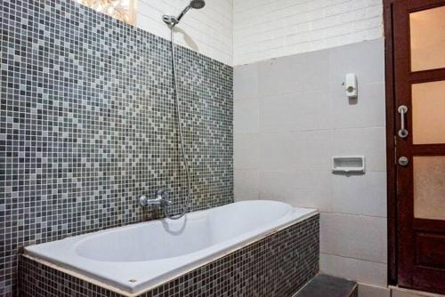 een badkamer met een bad en een douche bij Homestay Jro Mangku Gede House in Penginyahan