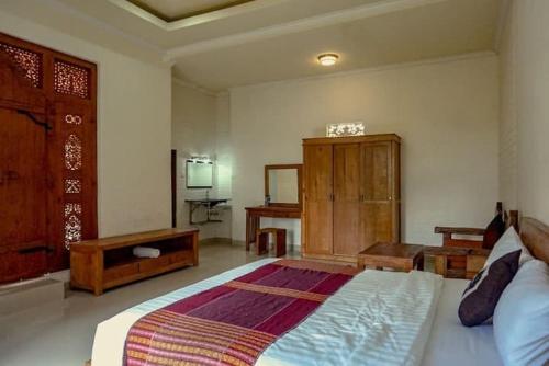een slaapkamer met een groot bed en een houten kast bij Homestay Jro Mangku Gede House in Penginyahan