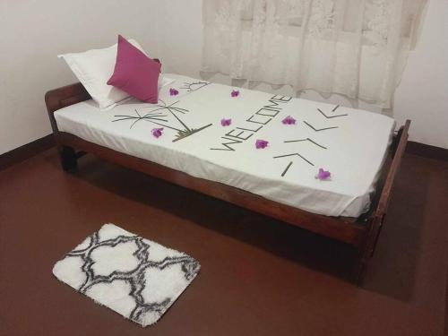 a bed with white sheets and purple flowers on it at Laliz in Hikkaduwa