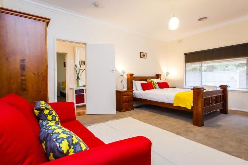 a bedroom with a bed and a red couch at Indulge Homes - 77 Olive in Mildura