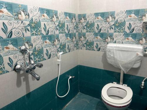 a bathroom with a toilet with blue and white tiles at Goroomgo Hasabasa Puri 100 Meter From Beach in Puri