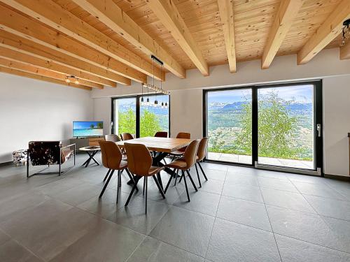 een eetkamer met een tafel, stoelen en ramen bij My Mountain Paradise - Swiss Alps in Rechy