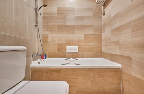 La salle de bains est pourvue de toilettes et d'une baignoire. dans l'établissement Village Hotel Bugis by Far East Hospitality, à Singapour