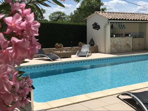 une piscine avec deux chaises et une maison dans l'établissement Villa climatisée avec piscine, à Pont-Saint-Esprit