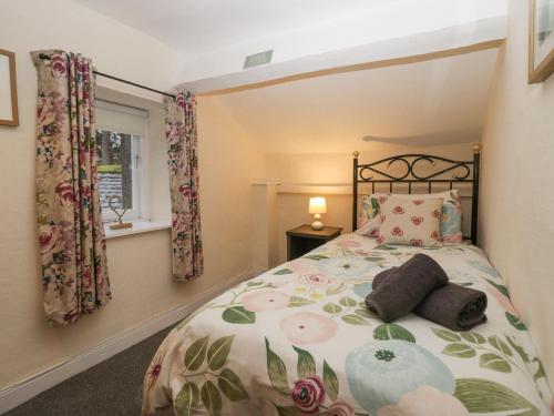 une chambre avec un lit avec un couvre-lit fleuri dans l'établissement Nook Cottage, à Keswick
