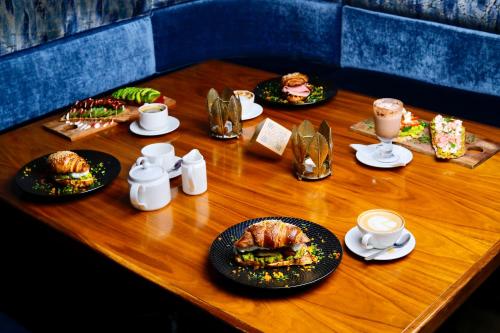 a wooden table with plates of food and cups of coffee at Colosseum Boutique Hotel & Spa in Dar es Salaam
