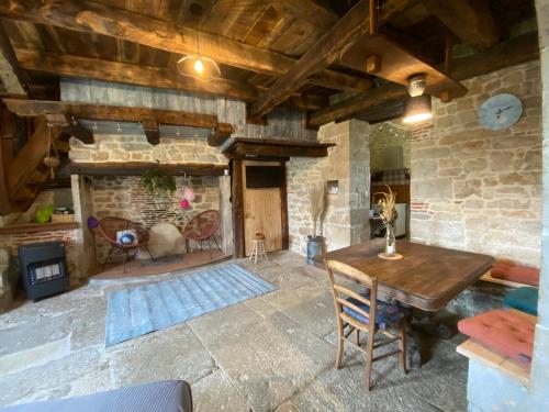 a living room with a wooden table and a stone fireplace at Gîte de Lespinasse in Saint-Cernin