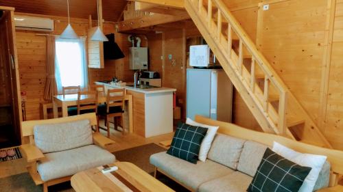 a living room with a staircase in a log cabin at ふらの田園コテージヌプリ in Nakafurano