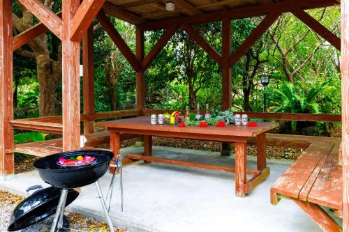 a wooden gazebo with a table and a grill at Cottage Muinochichi in Motobu