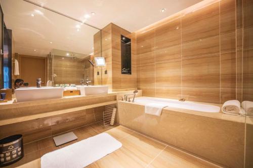 bagno con ampia vasca e lavandino di HongQiao Primus Residence Apartment - National Exhibition Center a Shanghai