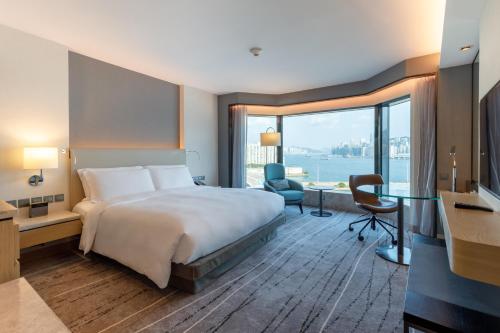 a hotel room with a bed and a large window at New World Millennium Hong Kong Hotel in Hong Kong