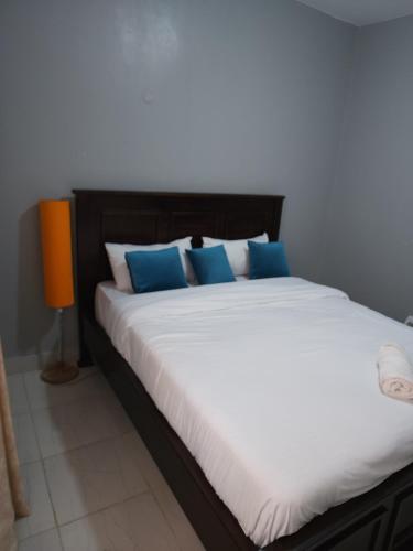 a large white bed with blue pillows in a room at Wanderlust Haven in Thika