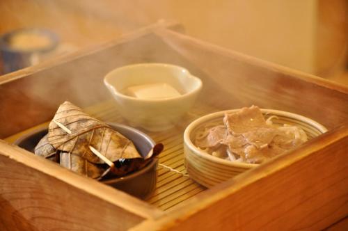 a wooden box with two bowls and a bowl of food at Okuhida Garden Hotel Yakedake in Takayama