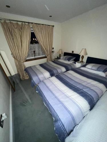 a bedroom with two beds and a window at Broxbourne Two-Bedroom Apartment Close To Amenities in Hoddesdon
