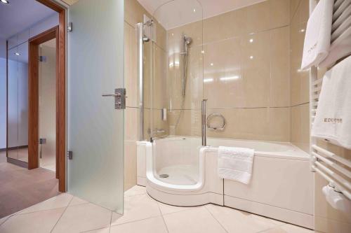 a bathroom with a shower and a tub and a toilet at Hotel EDELWEISS Berchtesgaden Superior in Berchtesgaden