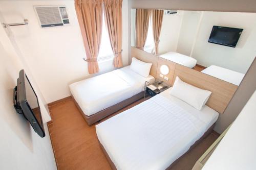 Habitación pequeña con 2 camas y TV. en Red Planet Manila Malate Mabini en Manila