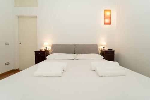 a bedroom with a large white bed with two night stands at appartamento a 500 metri da San Siro in Milan