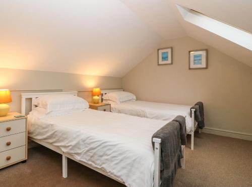 two beds in a attic bedroom with two lamps at Oak Cottage in Caernarfon