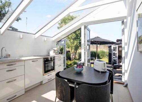 a kitchen with a table and a large window at Exclusive Architect Designed Beach House in Karrebæksminde