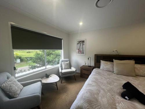 a bedroom with a bed and a chair and a window at Townhouse in Hope Island in Gold Coast