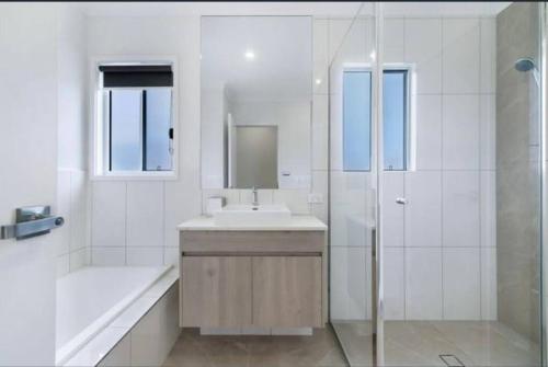 y baño blanco con lavabo y ducha. en Townhouse in Hope Island, en Gold Coast