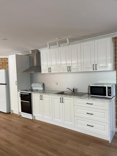 a kitchen with white cabinets and a microwave at Sandstone Family Apartment in Grindelwald