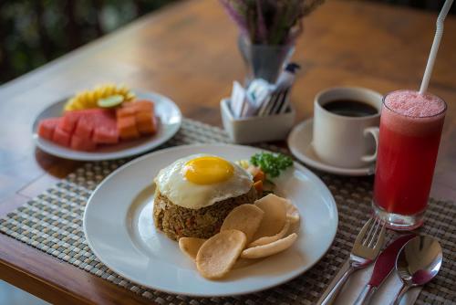 een tafel met twee borden ontbijtproducten en een drankje bij Padmasari Resort Lovina in Lovina