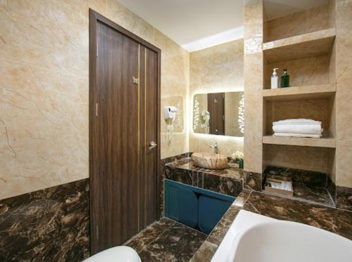 ein Badezimmer mit einer Badewanne, einem Waschbecken und einem Spiegel in der Unterkunft Bao Ngoc Hotel Linh Dam in Hanoi
