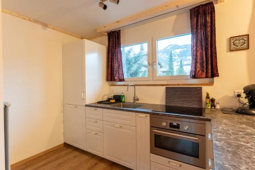 a kitchen with white cabinets and a sink and a window at Fresh & Simple near Gstaad in Gstaad