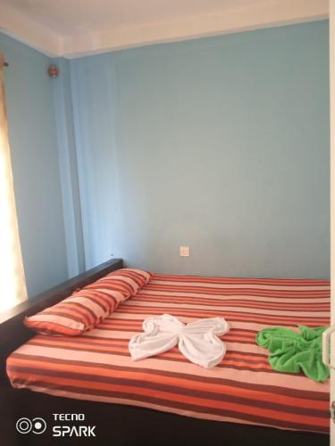 a bed with two pairs of white clothes on it at Ranven hotel dampe in Piliyandala