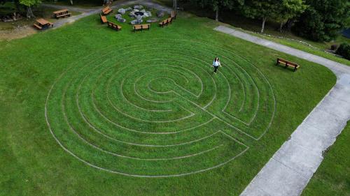 a person standing in front of a maze in the grass at Art of Living Retreat Center - All Inclusive - Mountain Top Wellness Retreat in Boone