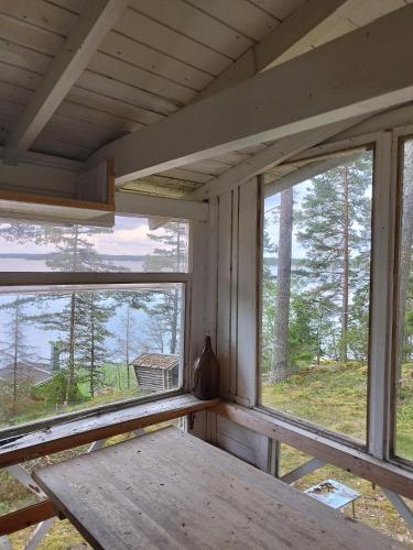 um quarto com duas janelas e uma mesa de madeira em Topsala Seaside em Houtskari