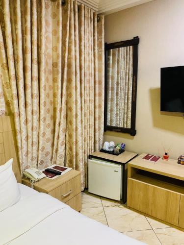 a hotel room with a bed and a television at Bays Lodge, Accra in Accra