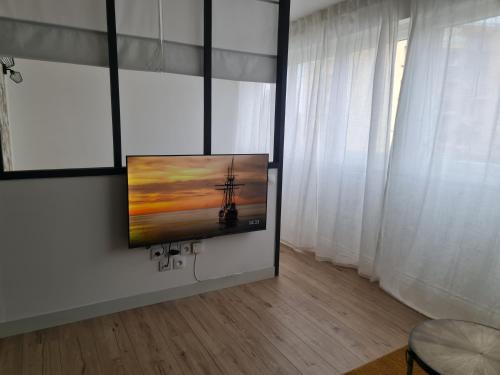 uma televisão de ecrã plano pendurada numa parede num quarto em Le Viva em Saint-Étienne