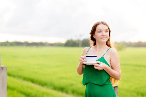 a woman in a green dress holding a cup of coffee at Serene Park Hotel By Ark in Tissamaharama