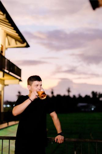 a young man drinking a glass of wine at Serene Park Hotel By Ark in Tissamaharama