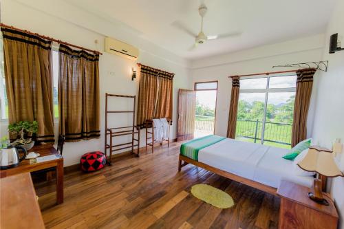 um quarto com uma cama, uma secretária e janelas em Serene Park Hotel By Ark em Tissamaharama