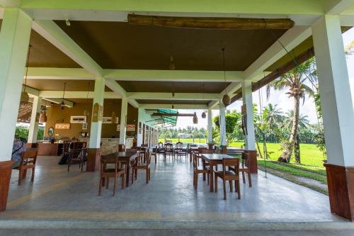 a restaurant with tables and chairs and palm trees at Serene Park Hotel By Ark in Tissamaharama