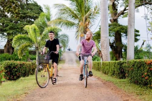 two people riding bikes down a dirt road at Serene Park Hotel By Ark in Tissamaharama