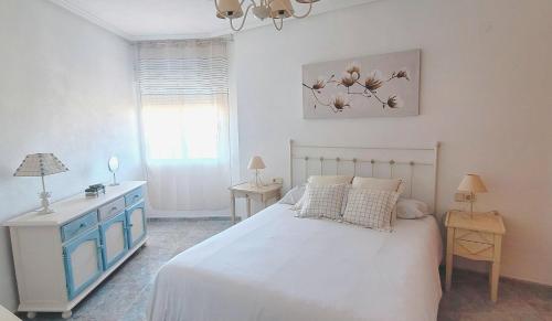 ein Schlafzimmer mit einem weißen Bett, einer blauen Kommode und einem Fenster in der Unterkunft Apartamento muy cerca del mar. in Arenales del Sol