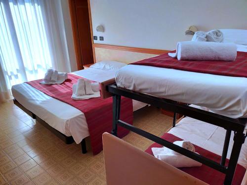 a hotel room with two beds and a chair at Ben Hur Rimini in Rimini