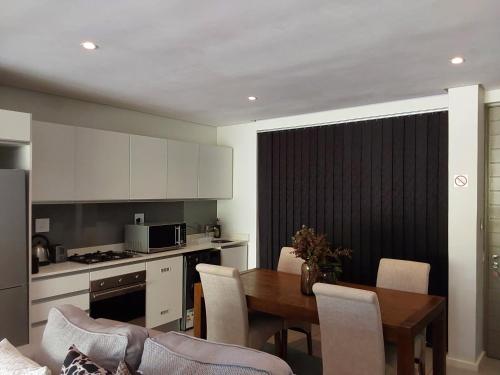 cocina y comedor con mesa y sillas en Dolce vita luxurious apartment, en Umhlanga