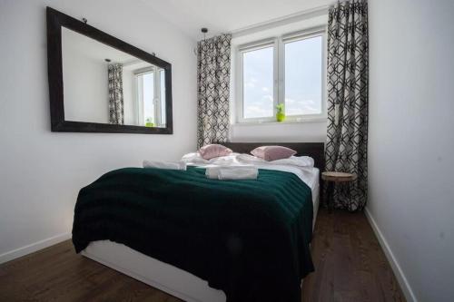1 dormitorio con 1 cama con espejo y ventanas en 1-Bedroom Warsaw Noakowskiego Apartment with City View by ECRU WWA55, en Varsovia