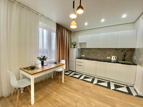 uma cozinha com armários brancos e uma mesa de madeira em Однокомнатные апартаменты ЖК Auezov city 37 em Almaty